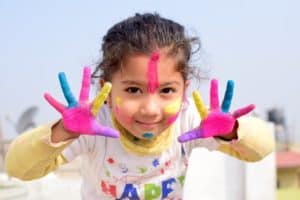 ילדה שמחה עם צבעים על הפנים והידיים